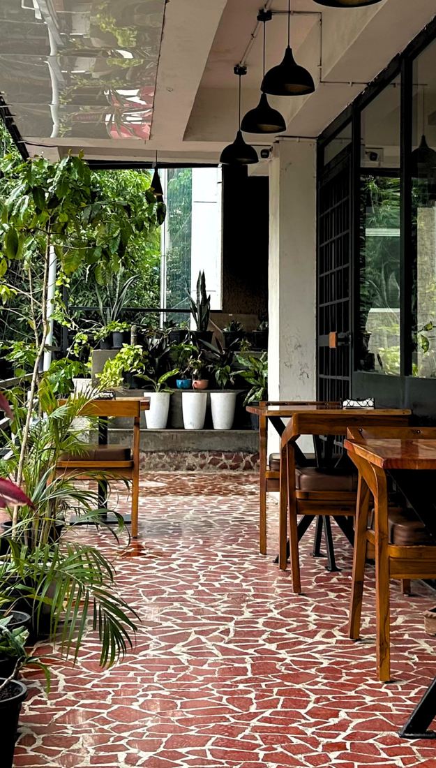Inside Handcrafted: wooden tables, plants and a red terrazzo floor